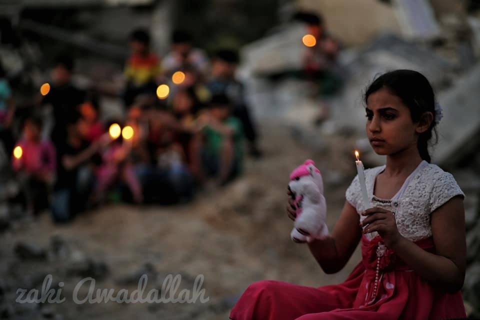 Les enfants palestiniens allument des bougies sur des décombres de maisons, démolis dans la dernière agression israélienne sur Gaza, en mémoire aux 27 vies assassinées par les machines d'Israël