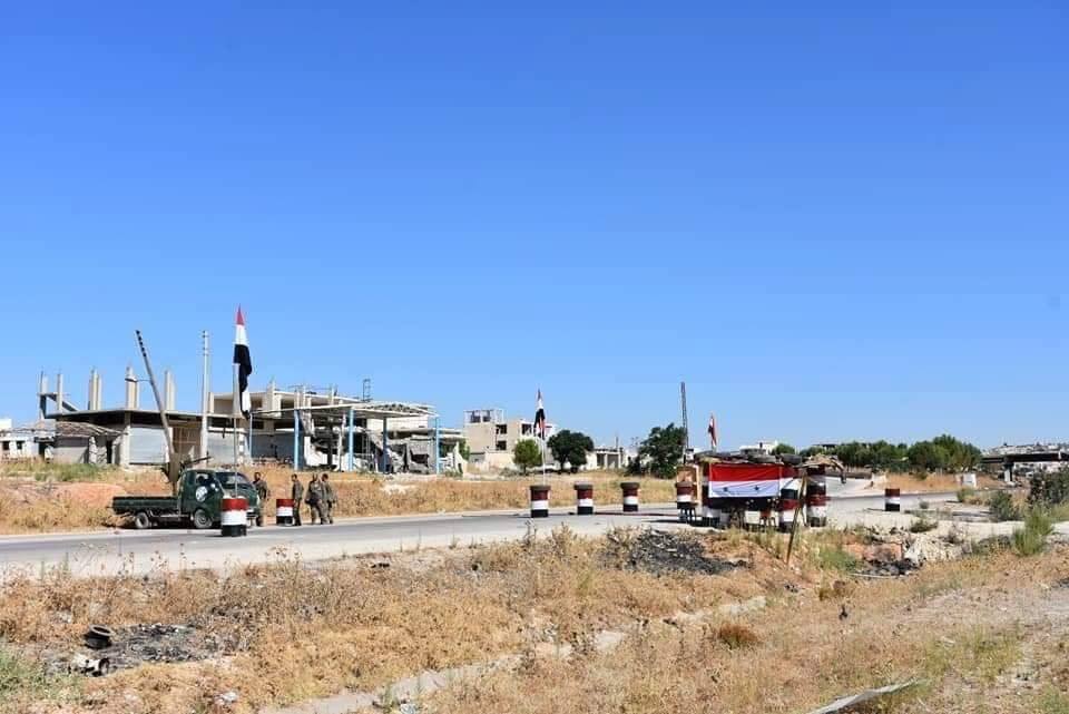 Les soldats de l'Armée Arabe Syrienne élèvent le drapeau Syrien et le portrait du défunt Président Hafez Al Assad à Khan sheikhoun