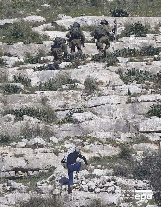 un jeune palestinien suit des soldats israéliens avec une pierre à la main dans la ville de Qafr qaddum dans le nord de la Cisjordanie occupée